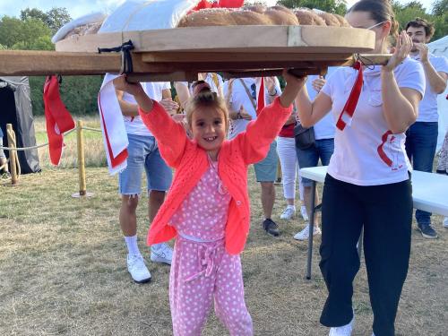 Iconographie - Une petite fille s’essayant au portage de la brioche avec des jeunes des Joyeux Vendéens du Boupère