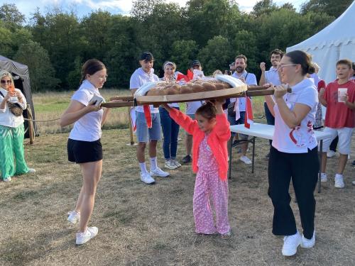 Iconographie - Une petite fille s’essayant au portage de la brioche avec des jeunes des Joyeux Vendéens du Boupère