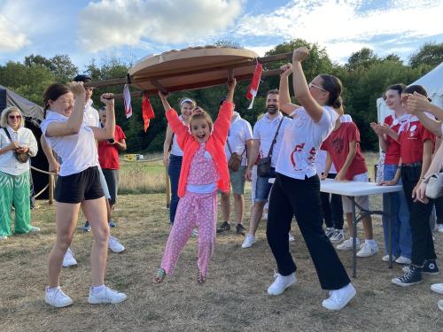 Iconographie - Une petite fille s’essayant au portage de la brioche avec des jeunes des Joyeux Vendéens du Boupère