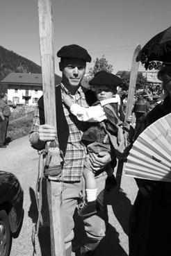 Iconographie - Reconstitution de geste à la Fête du costume - Skieur portant un enfant